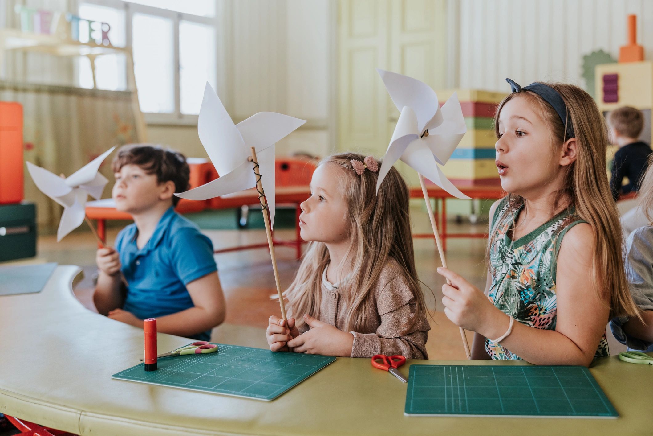 Children making paper crafts together in a classroom