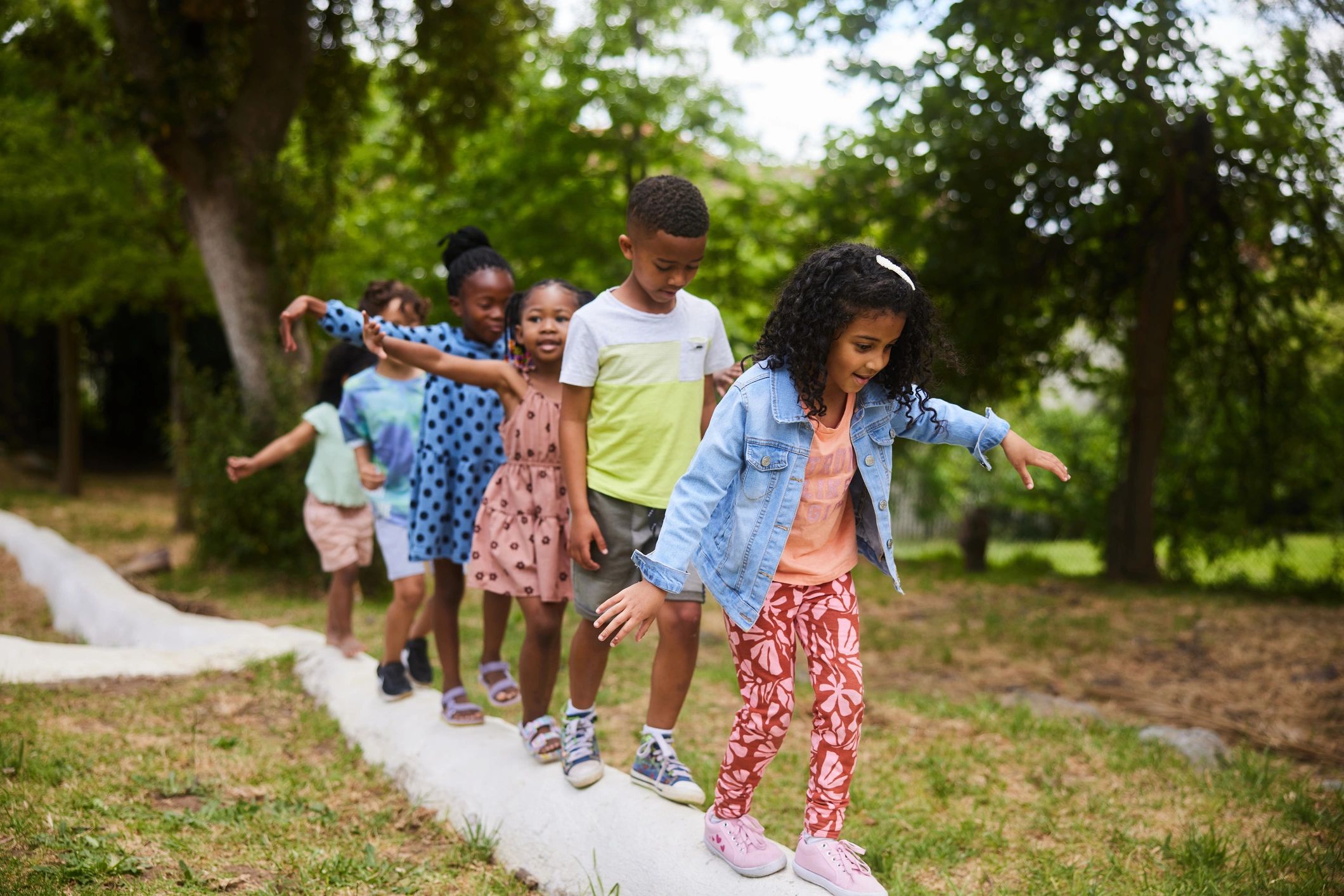 Children balancing and playing together outdoors in a park