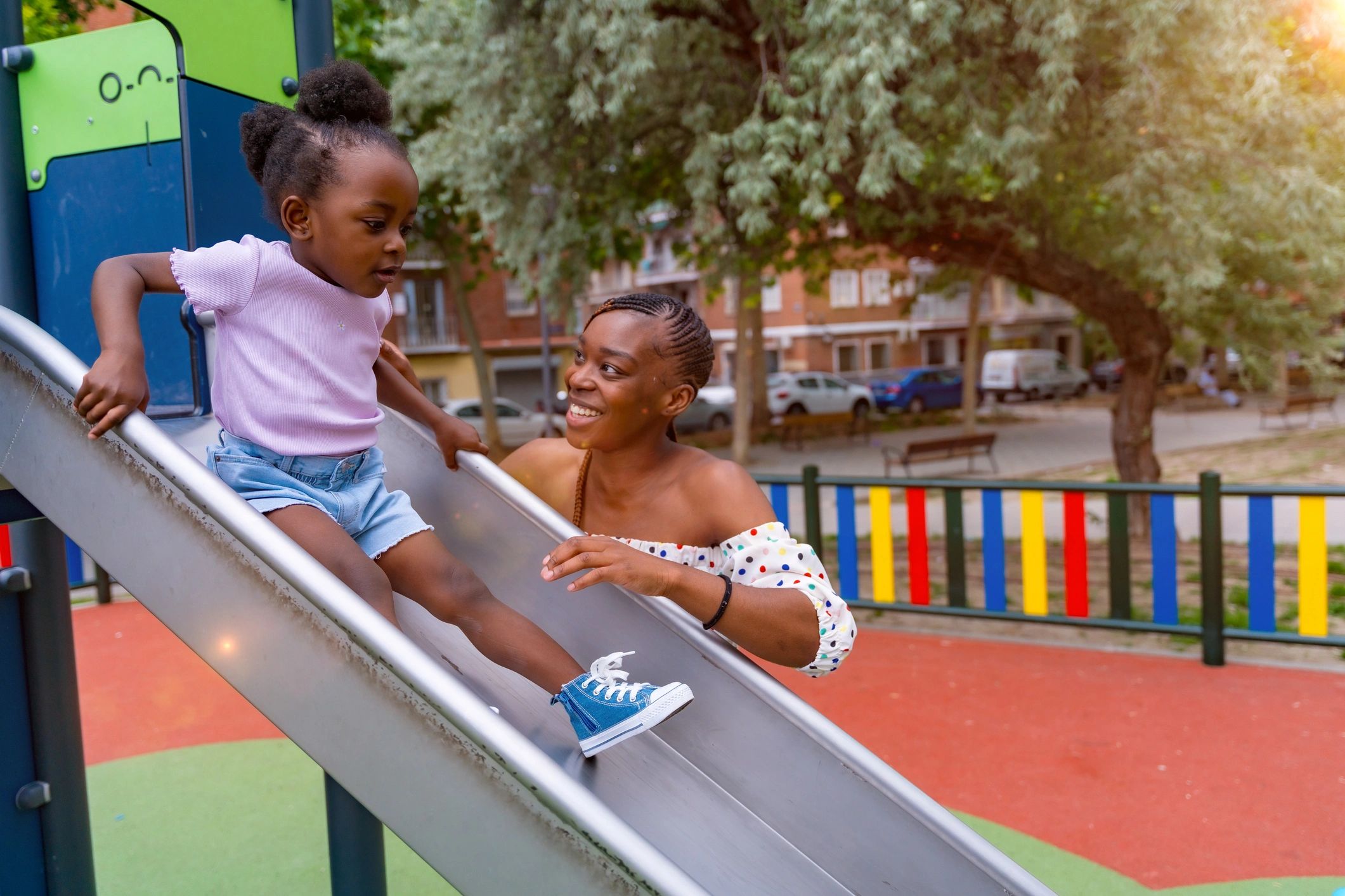 Mother and daughter playing at a playground at sunset