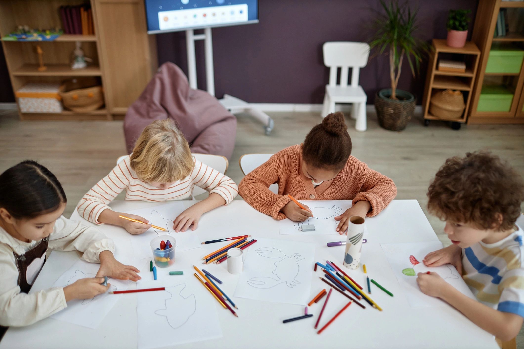 Top view of children doing arts and crafts at a preschool table