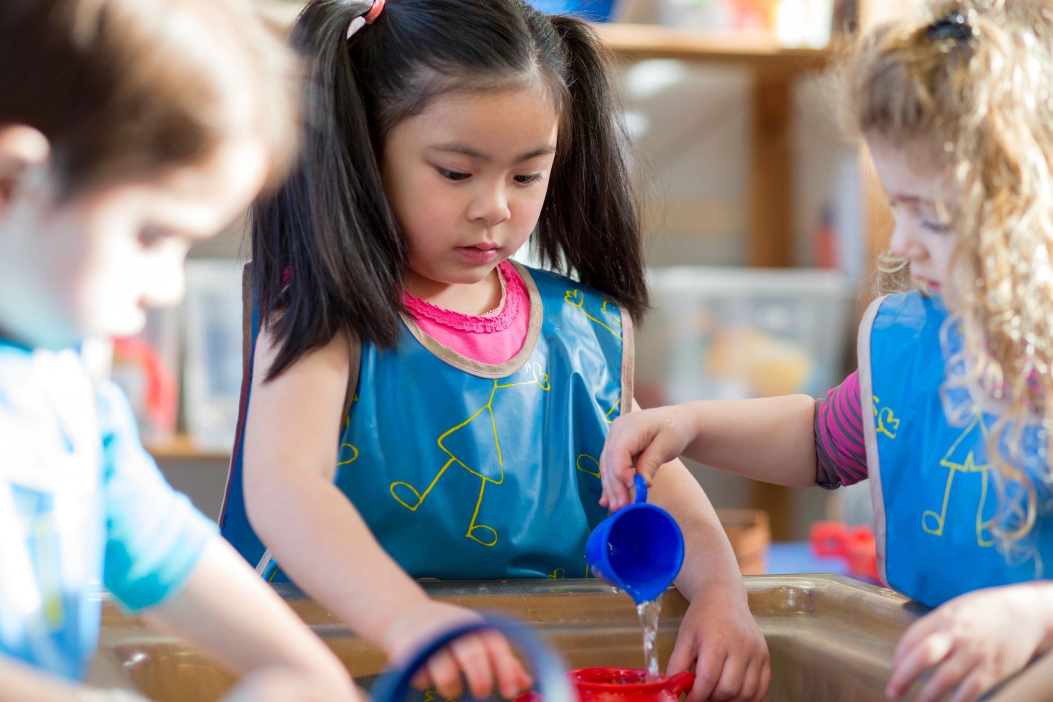 Children playing together at a water table in a nursery classroom